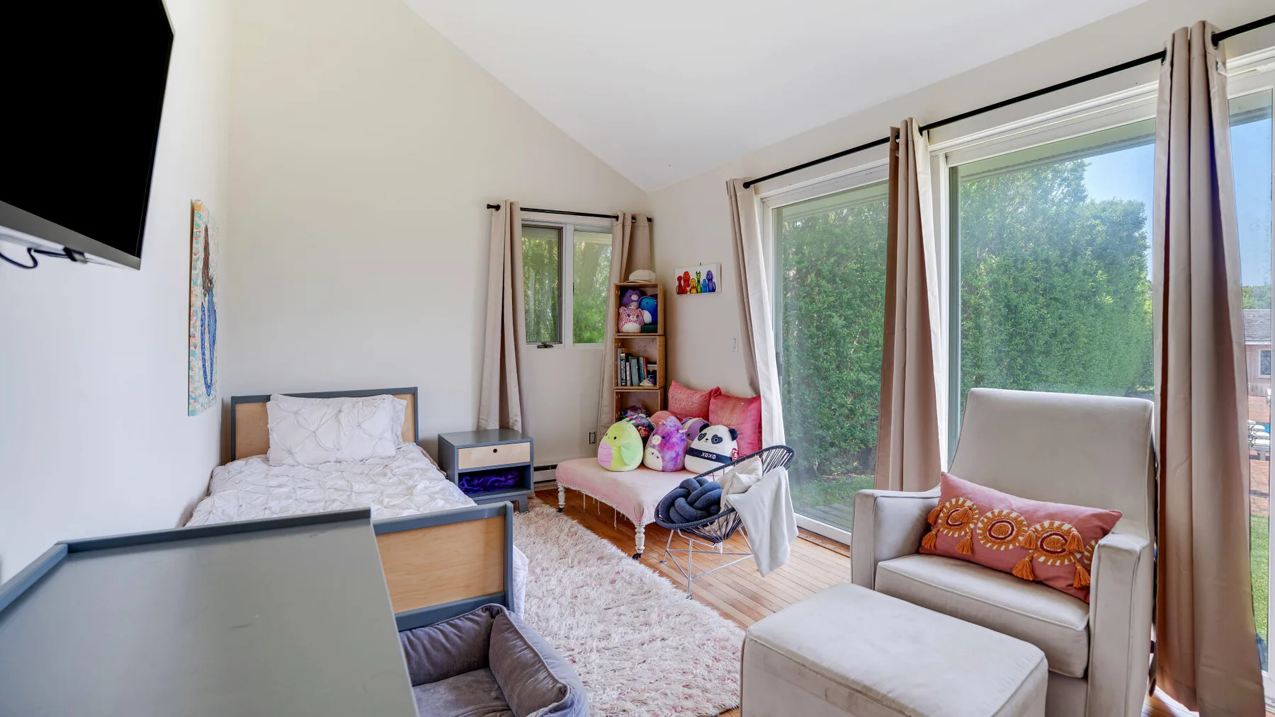 A bright bedroom and sitting area with large windows and a bed.