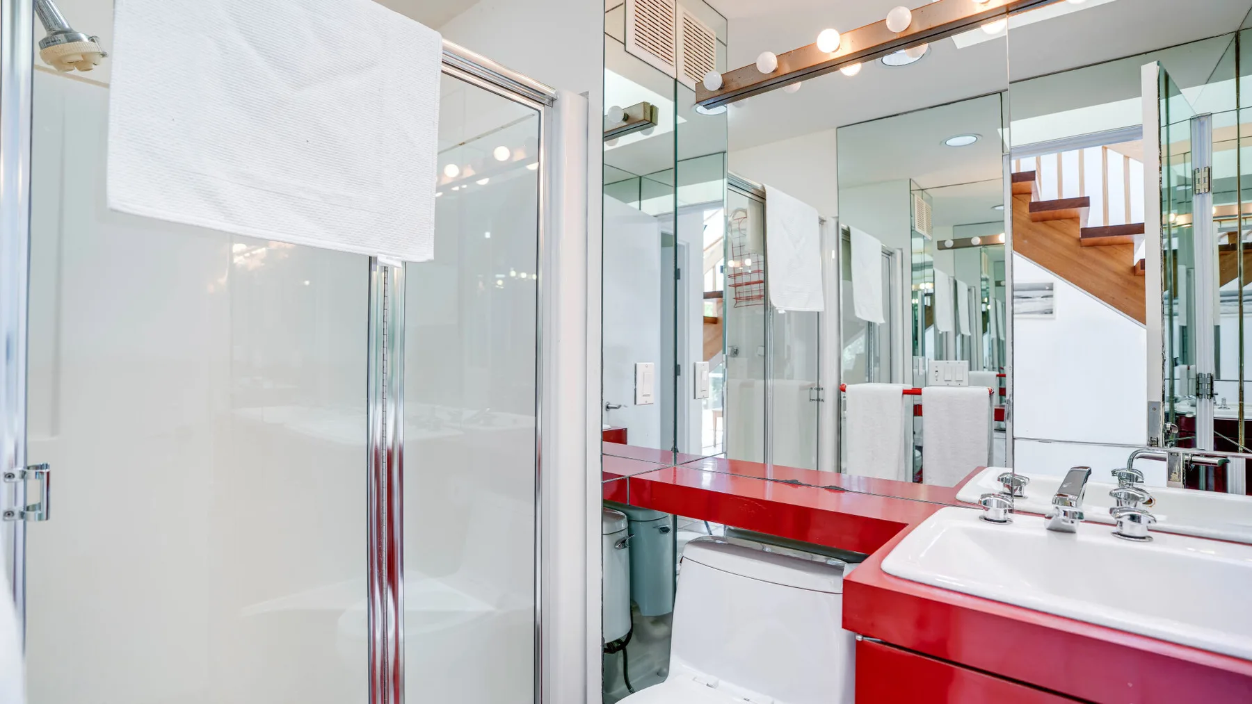 A bathroom with a red vanity and a large mirror.