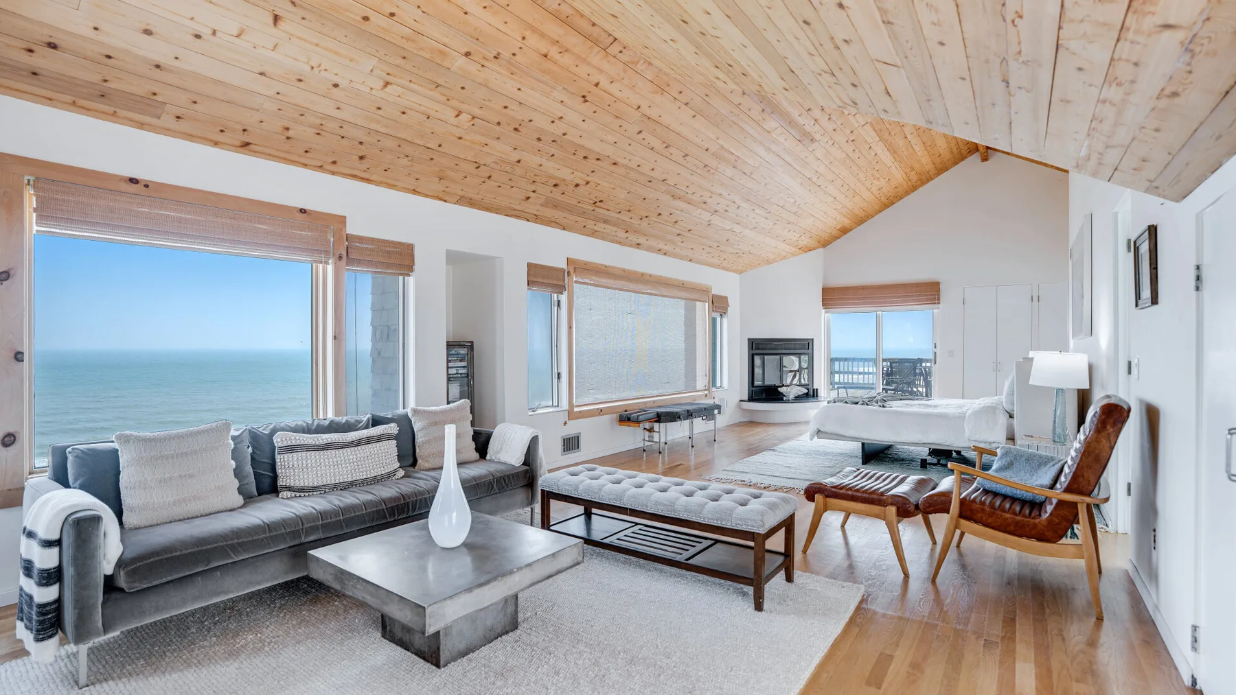A bright living room with large windows overlooking the ocean and a seating area.