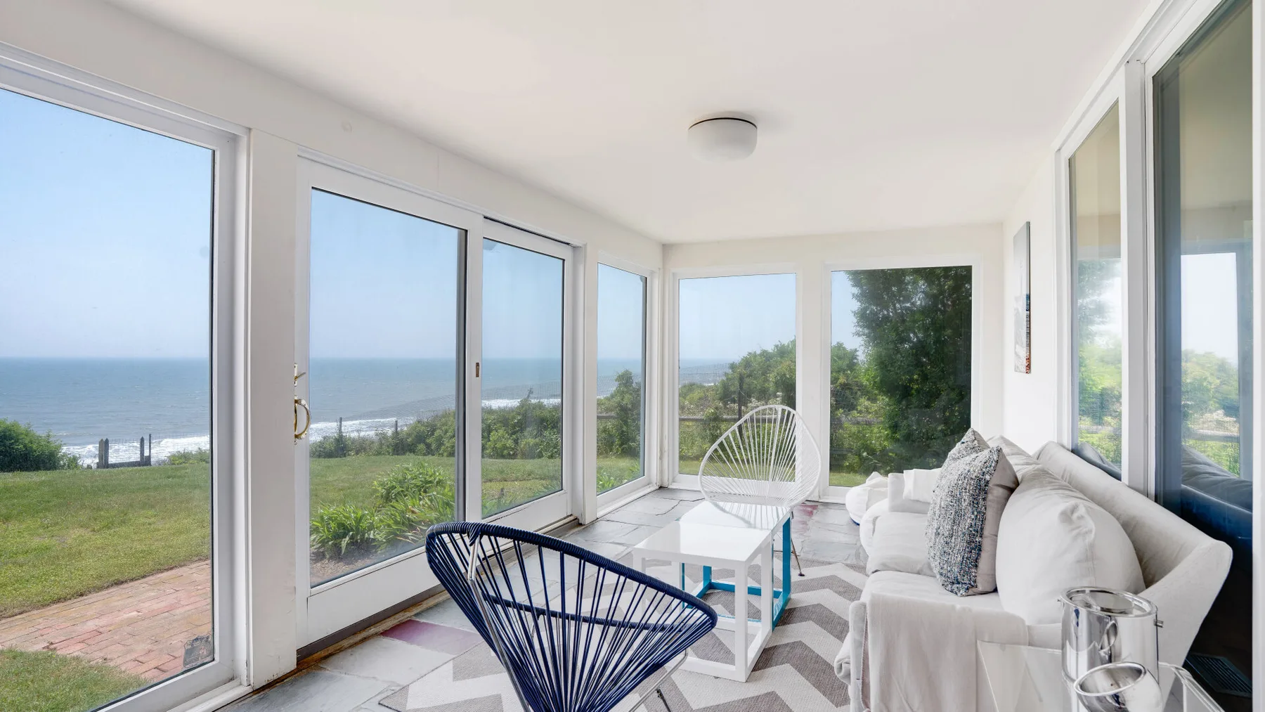 A bright living area with seating and broad windows overlooking the water.