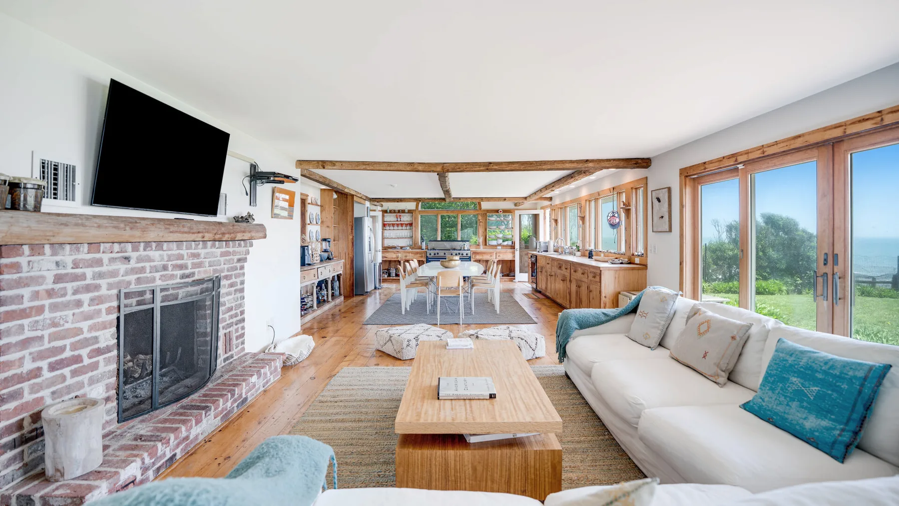 A bright living room with a fireplace, seating, and large windows overlooking the water.