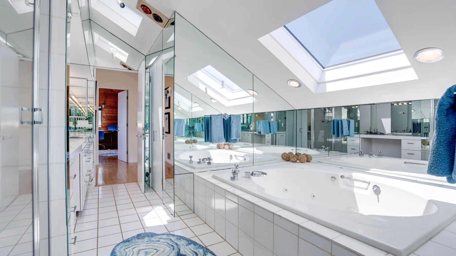 A bright bathroom with a large bathtub and mirrored walls.