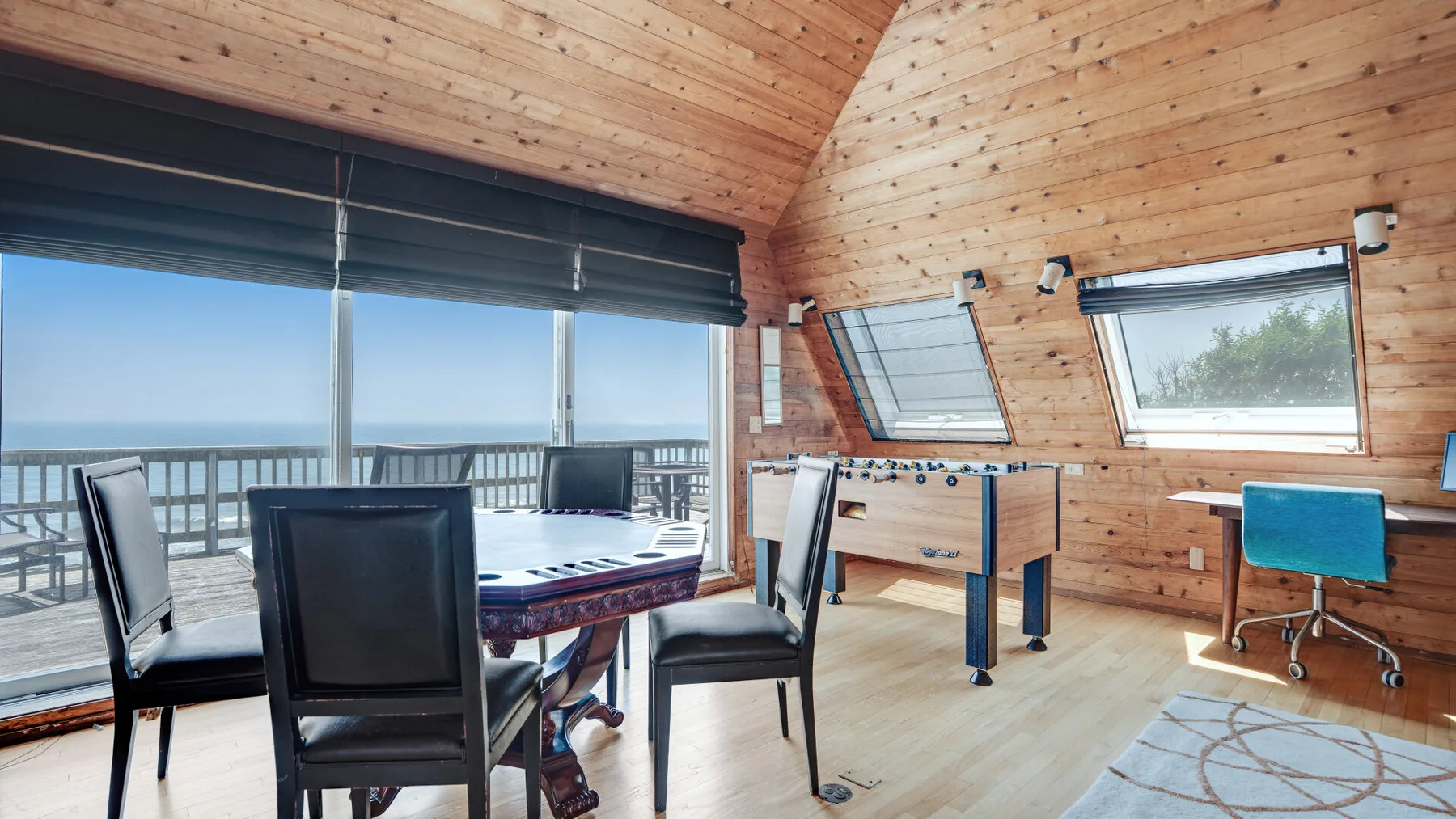 A wood-paneled game room with a pool table, seating, and large windows.