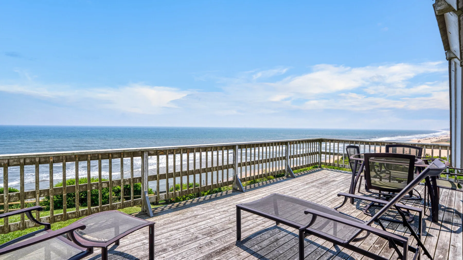 Una terraza junto al mar ofrece vistas al océano y tiene asientos al aire libre junto a la barandilla.