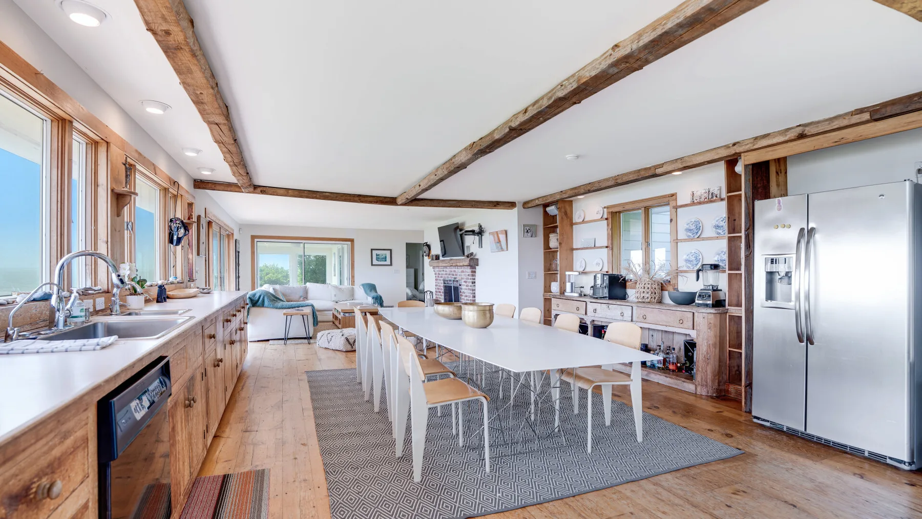 An open kitchen and dining area with a long table and exposed wooden beams.
