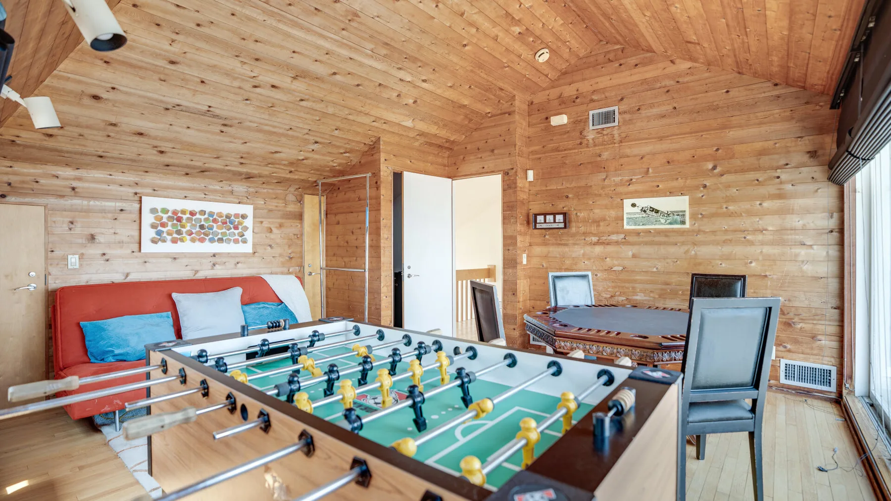 A wood-paneled game room with a foosball table and seating.