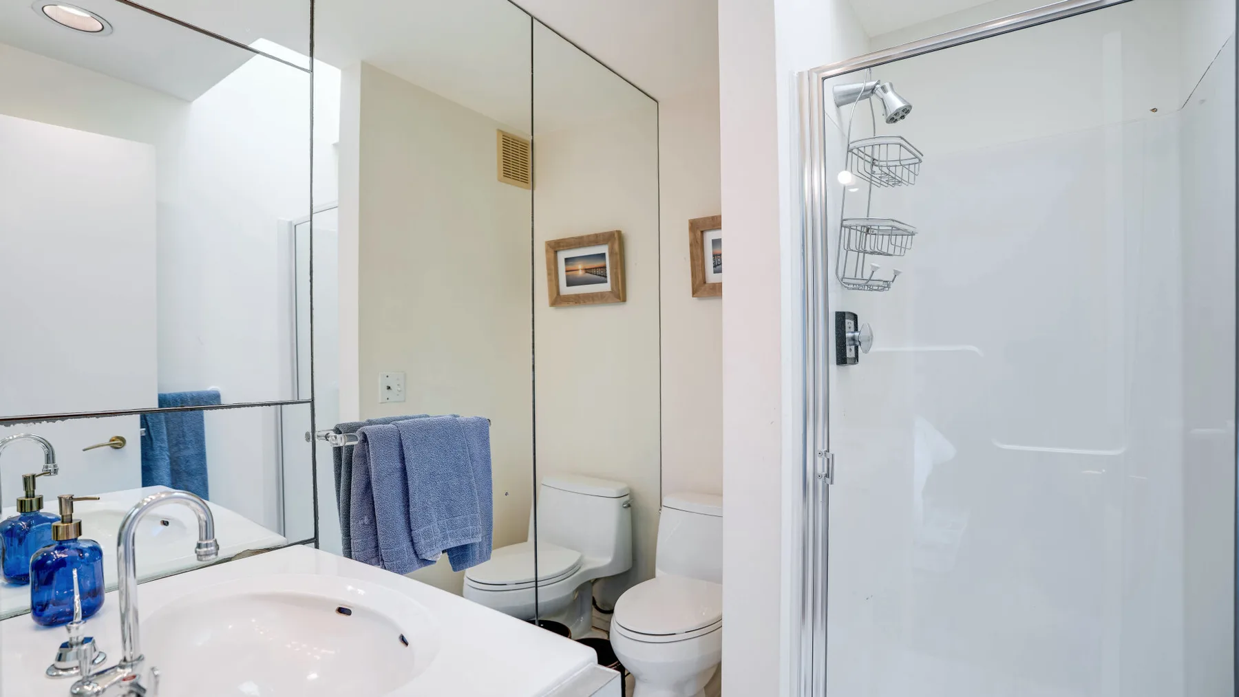 A bathroom with a sink, mirrors, and a glass shower.
