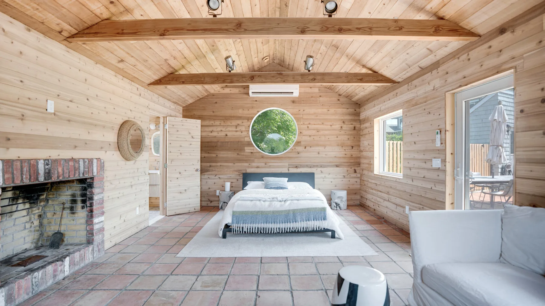 A wood-paneled bedroom with a bed, a fireplace, and seating.