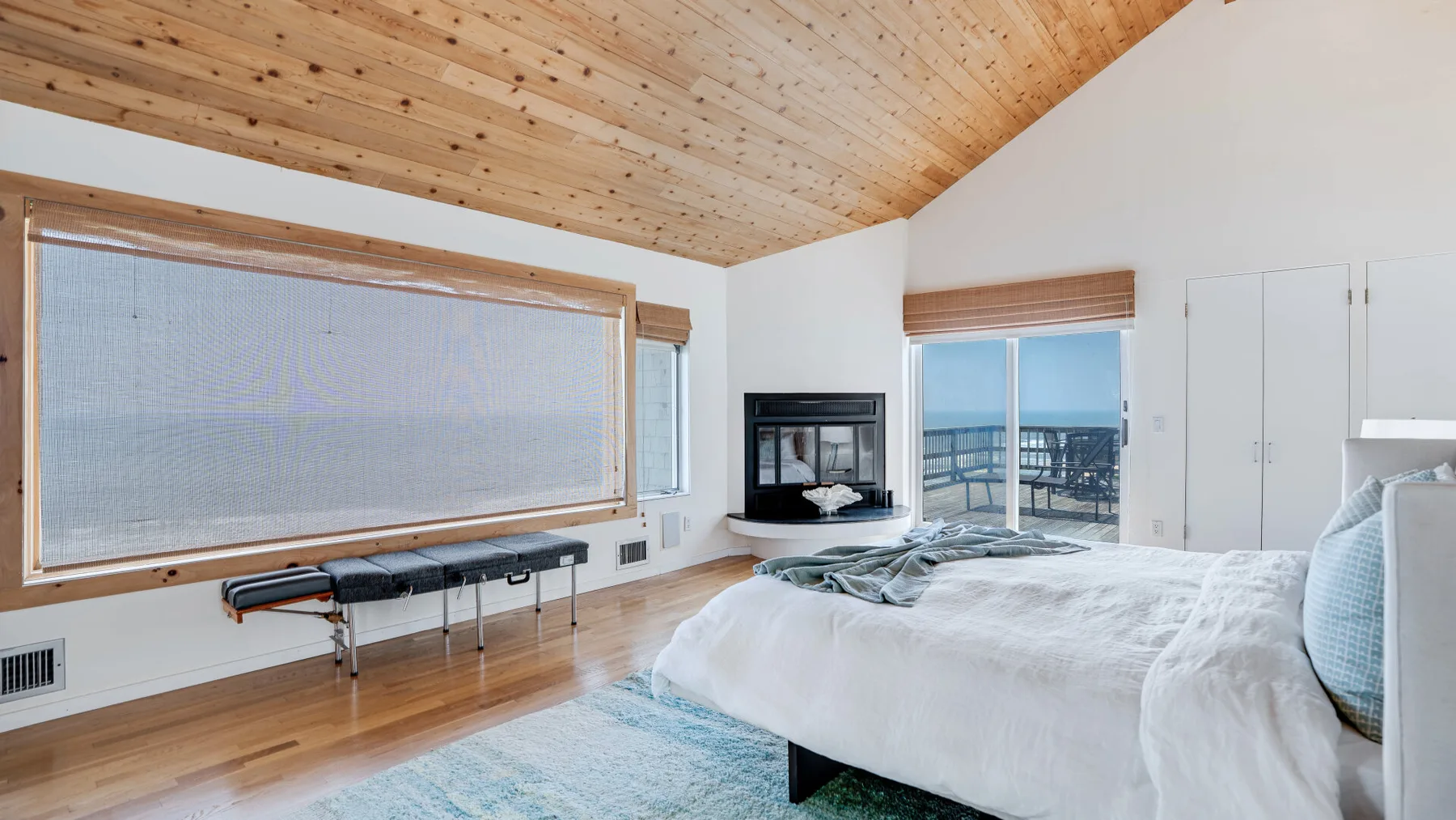 A bright bedroom with a large bed and a wood-paneled ceiling.