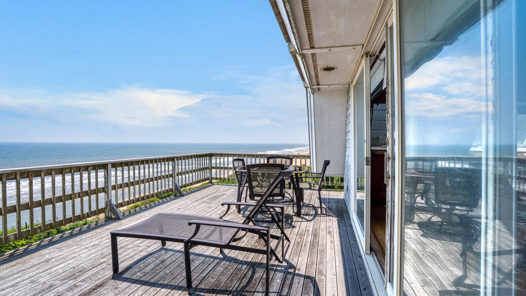 A wooden deck with outdoor seating overlooks the ocean.