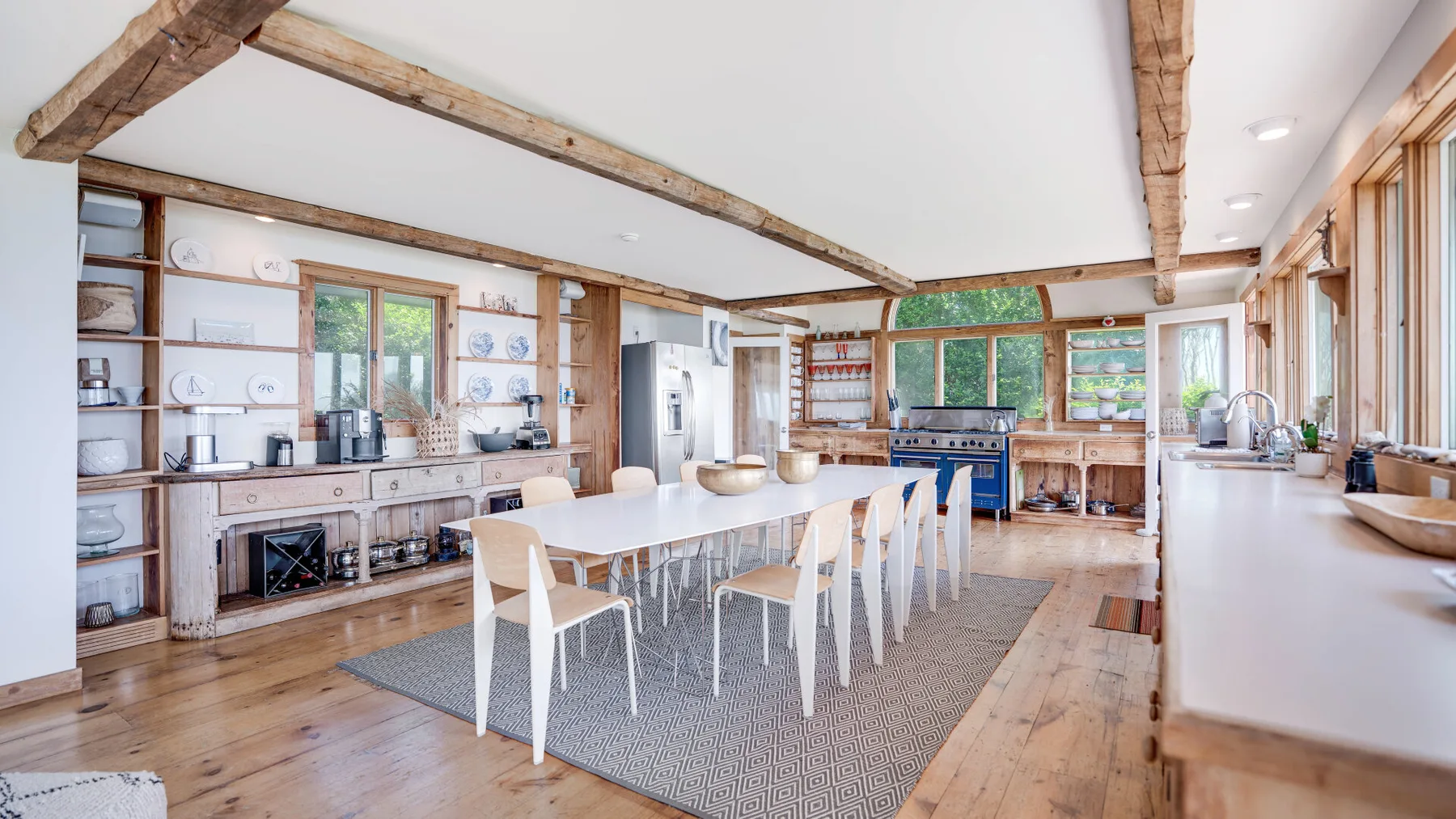 A bright dining area with a long table beneath exposed wooden beams.