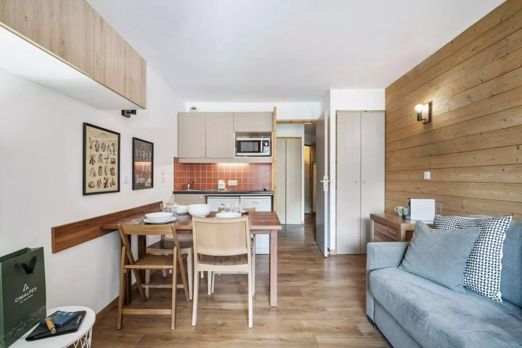 Una pequeña zona de estar y comedor incluye una mesa, asientos y una cocina.