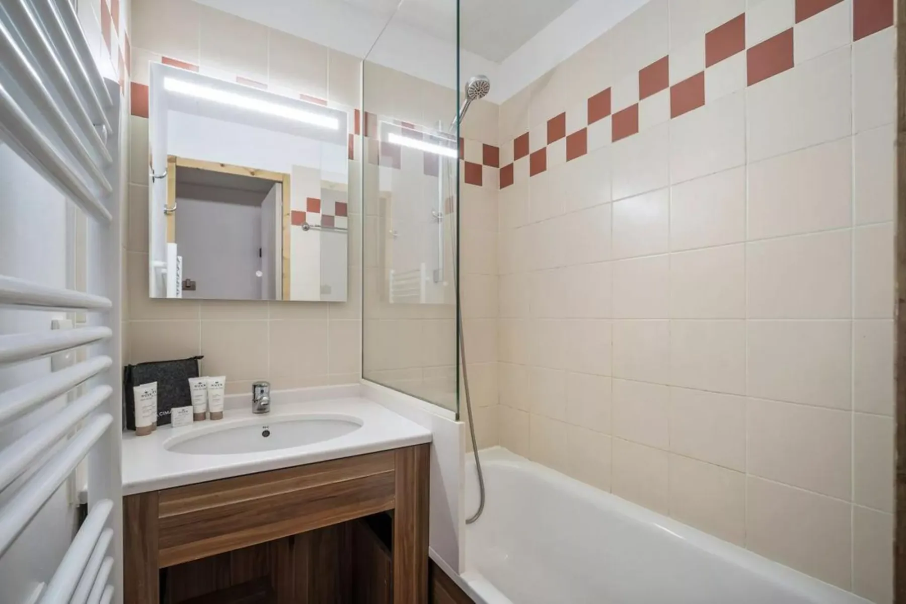 Un baño con azulejos, lavabo con mueble y bañera.