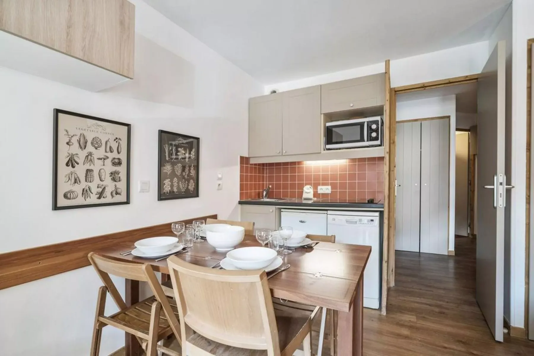 Un comedor con una mesa de madera está junto a una cocina compacta.