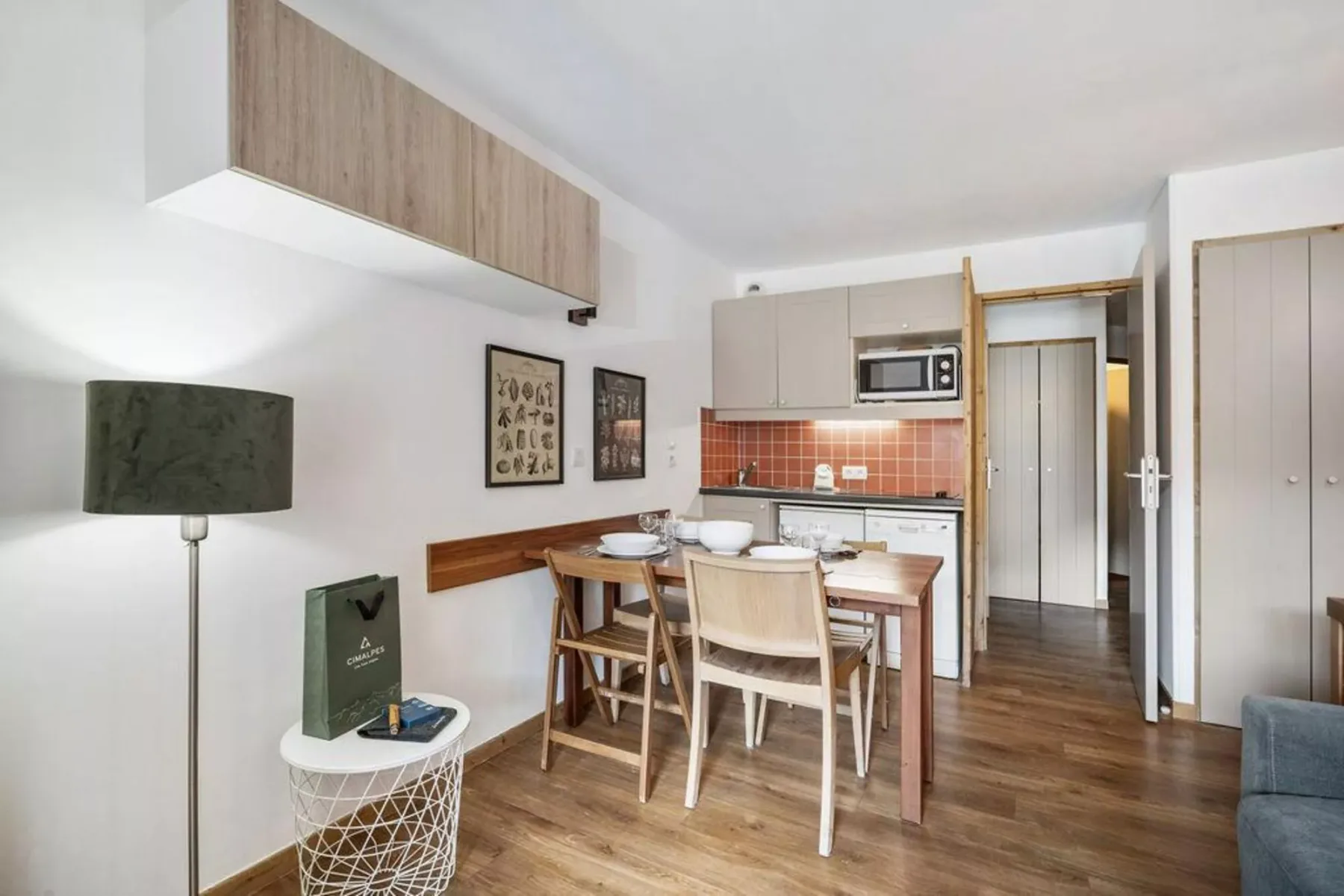 Comedor y cocina compacta con una mesa de madera y un salpicadero de azulejos rojos.