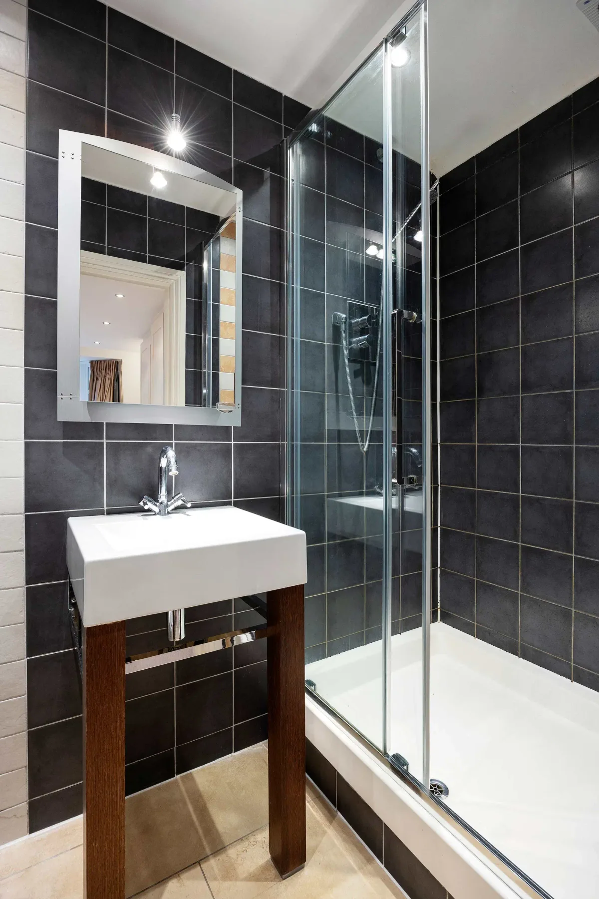 Un baño con azulejos, lavabo blanco y ducha de cristal.