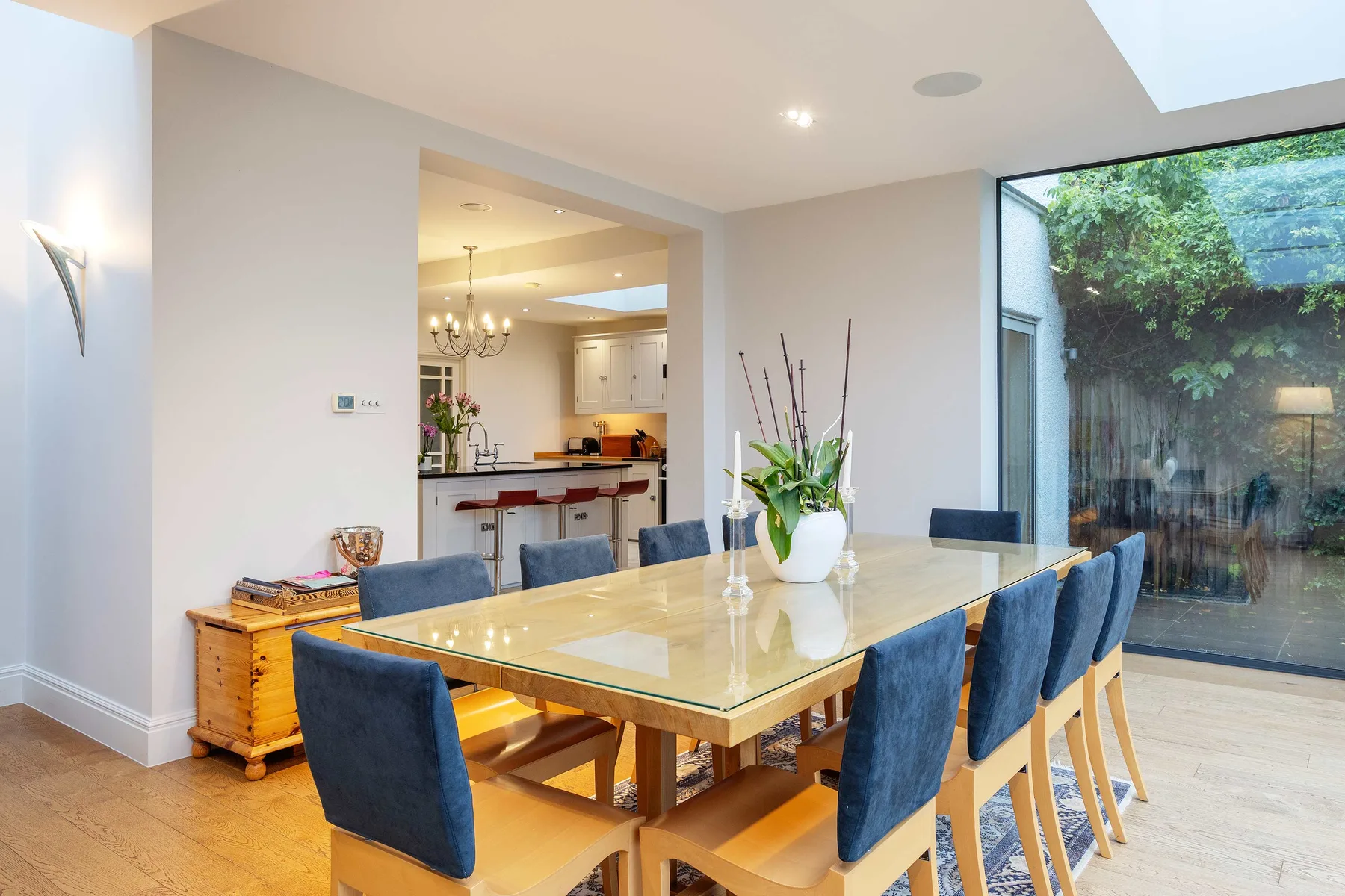 Comedor con una mesa de vidrio y asientos tapizados en azul.