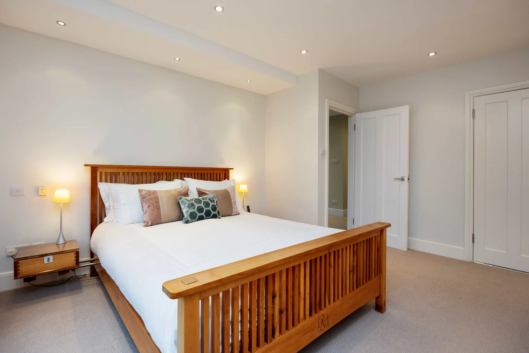 Un dormitorio con una cama de madera, ropa de cama blanca y lámparas de noche.