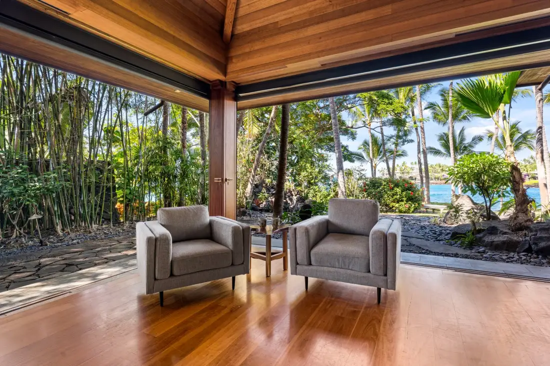 A sitting area with two armchairs opens onto a lush tropical garden.