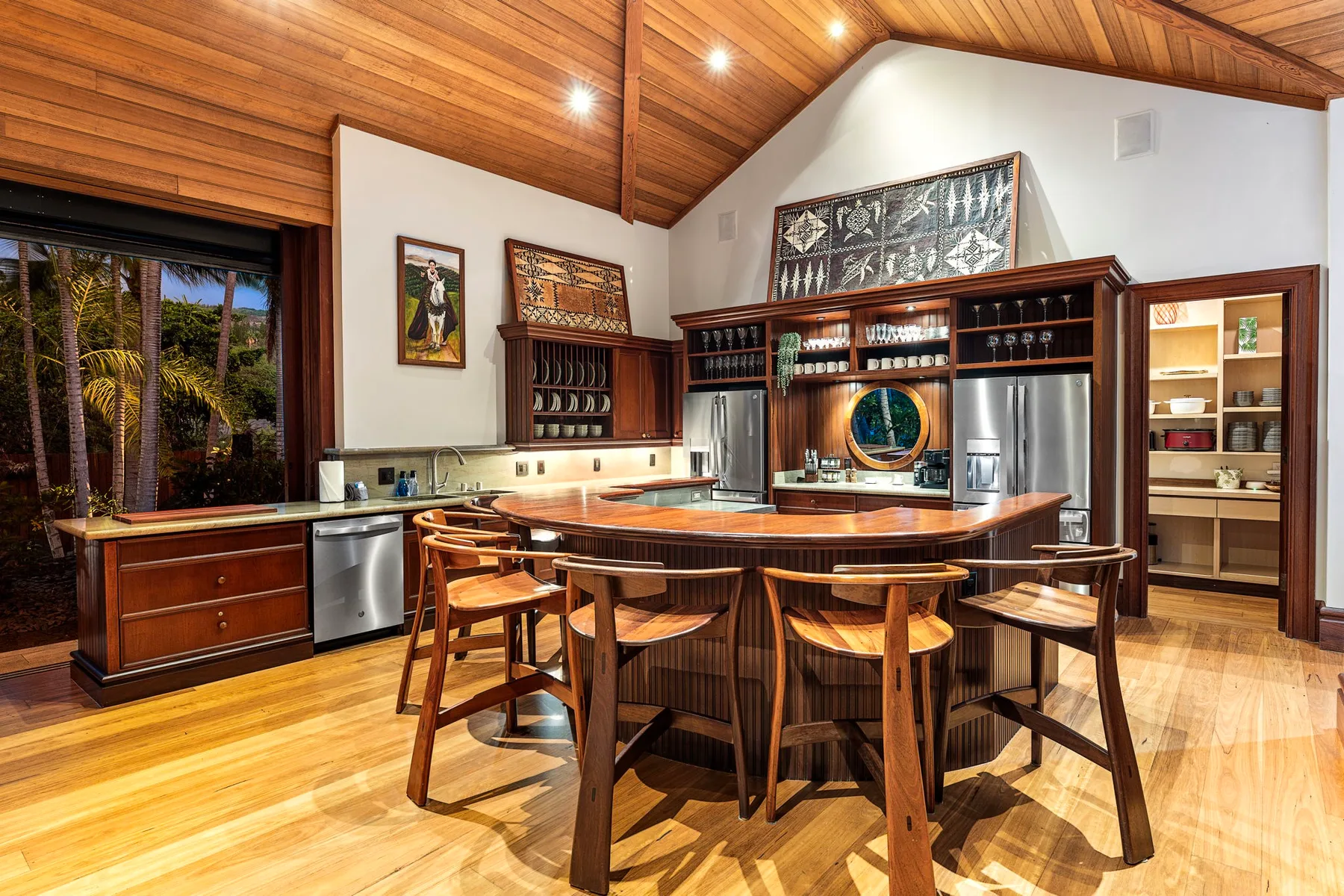 A spacious kitchen and dining area with a wooden island beneath a vaulted wood ceiling.