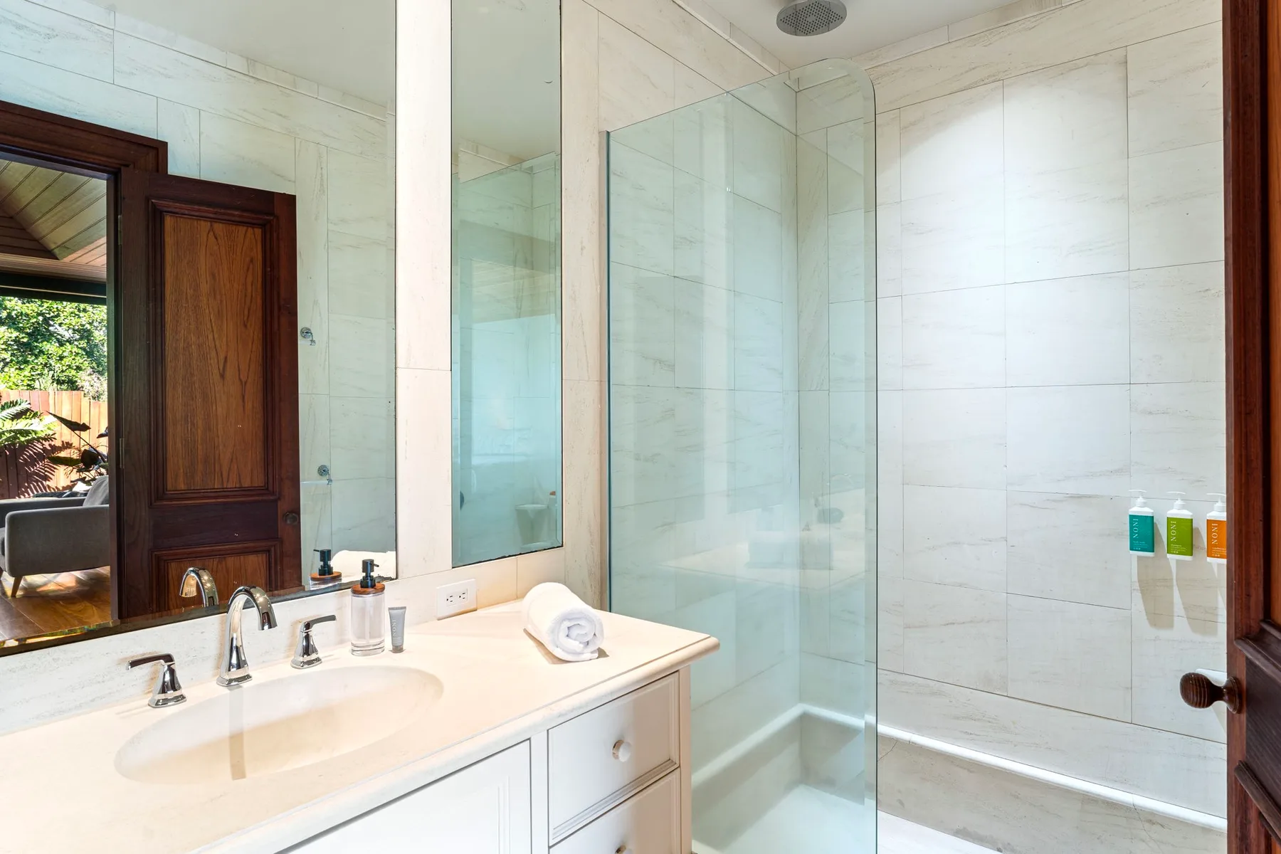 A bright bathroom with a vanity and glass-enclosed shower.