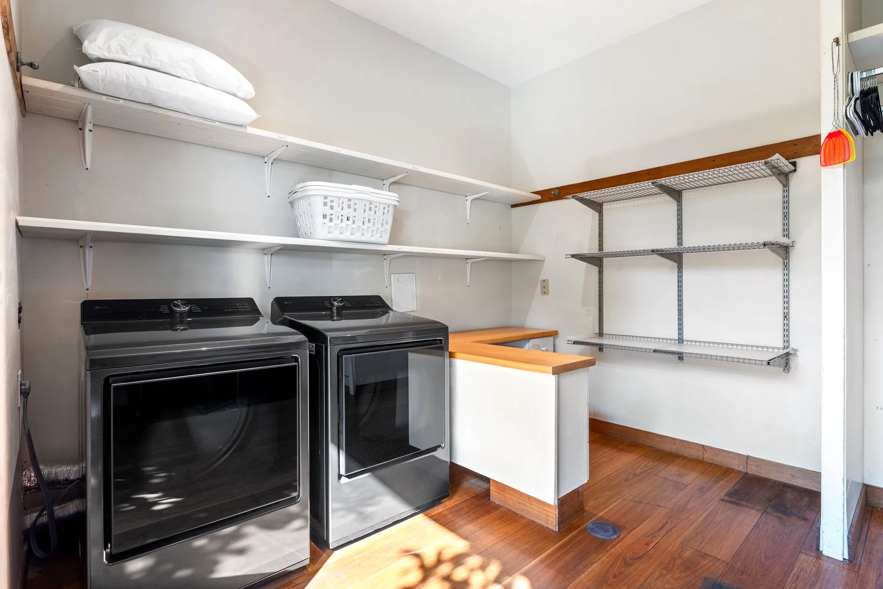 A laundry room with two machines, open shelving, and a folding counter.
