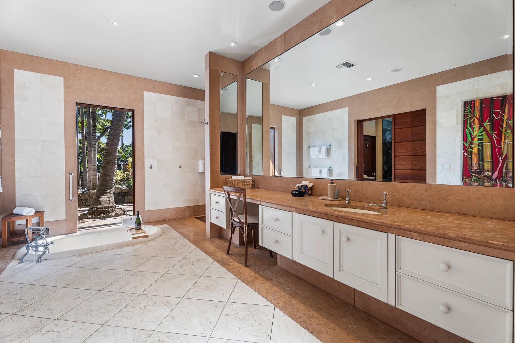 A spacious bathroom with a long vanity, large mirror, and a glass door opening to greenery.