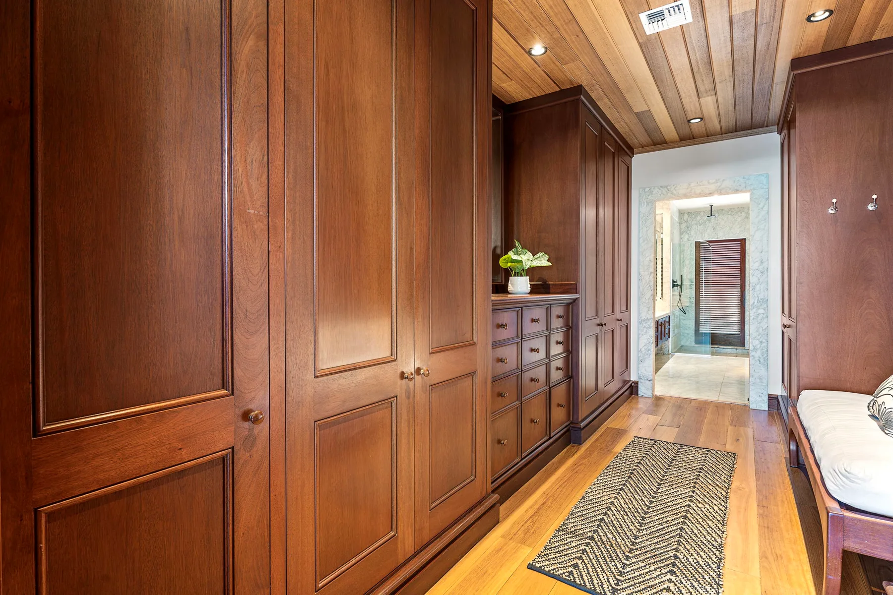 A wood-paneled dressing room with built-in cabinets and a runner rug.