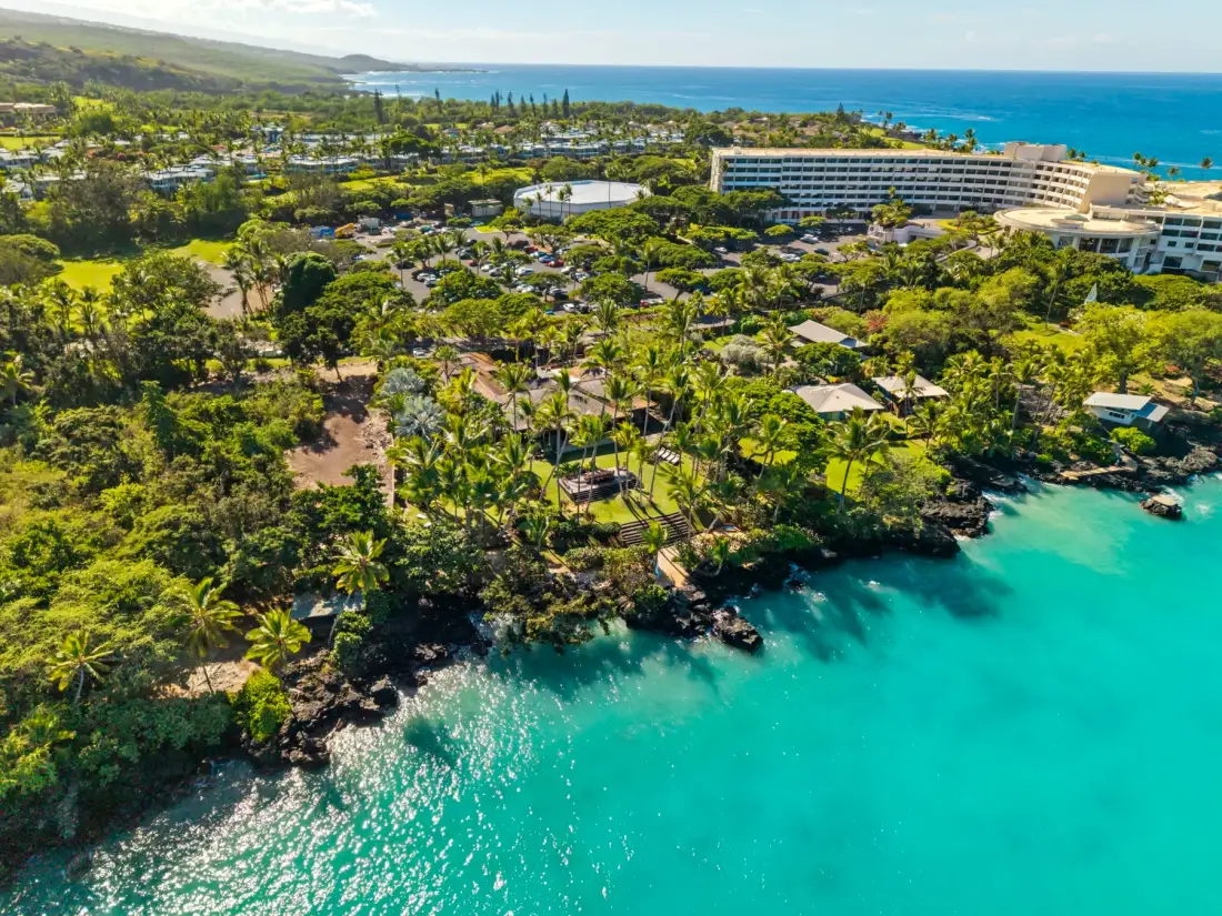 An aerial view of a tropical shoreline with turquoise water and resort buildings.