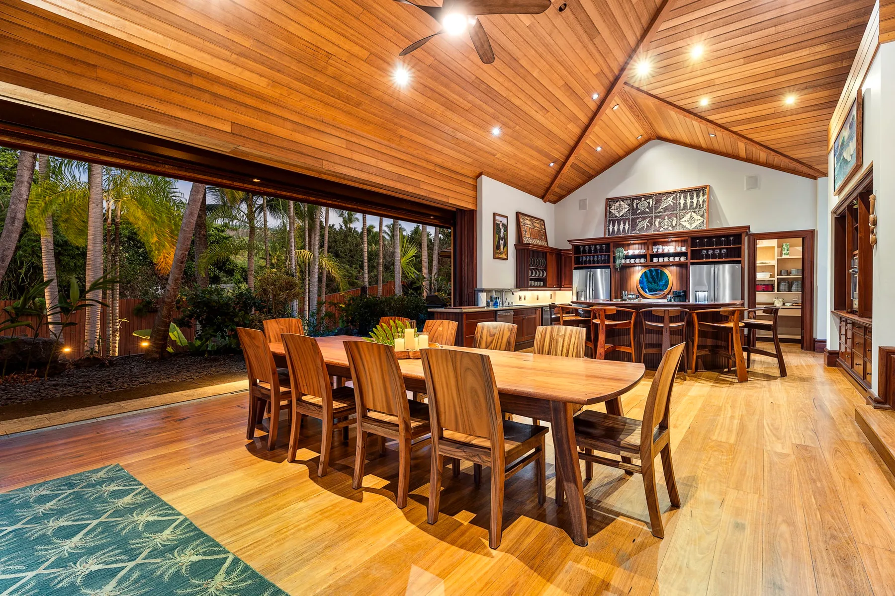A dining room with a long wooden table and chairs beneath a vaulted ceiling.