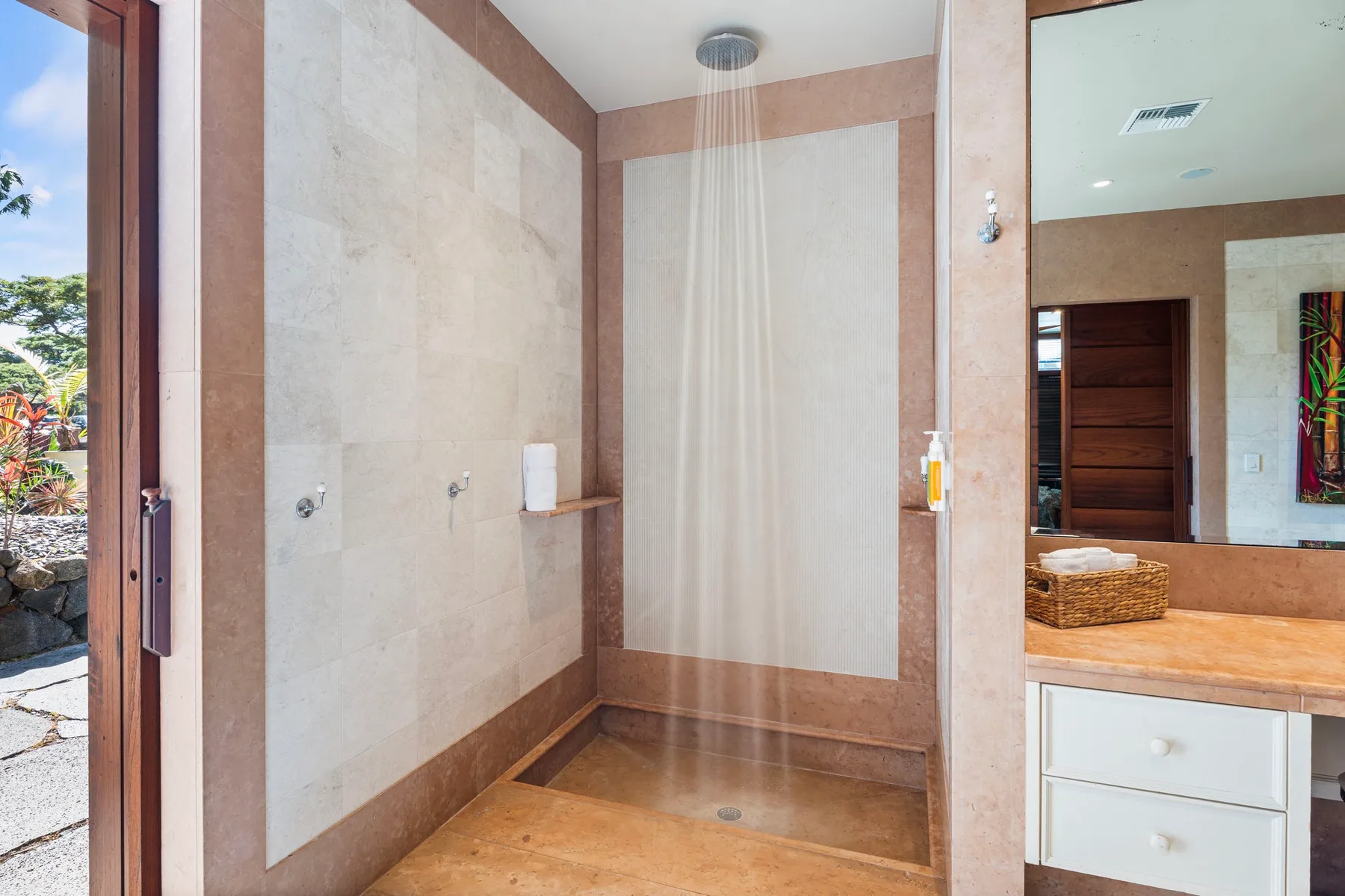 A tiled shower area with a rainfall showerhead and a glass door.