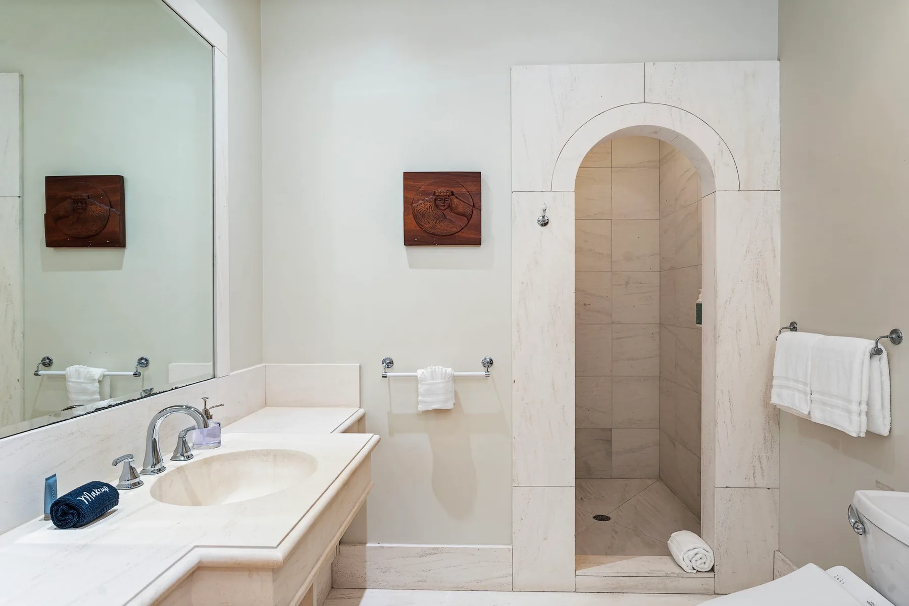 A bathroom with a sink, large mirror, and arched shower entrance.
