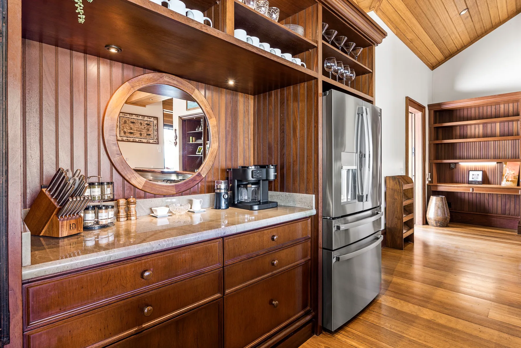 A wood-paneled kitchen with a counter, coffee maker, and stainless steel refrigerator.
