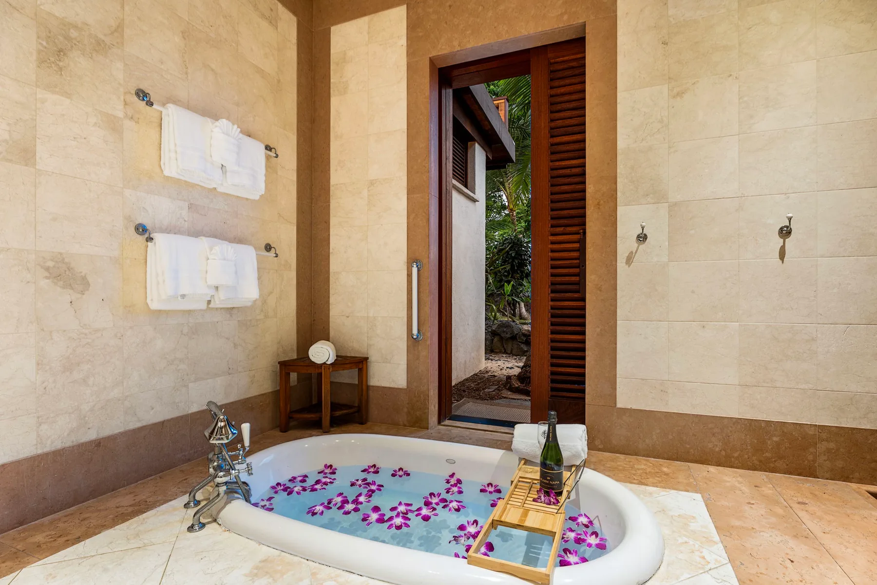 A bathroom features a soaking tub filled with water and scattered flower petals.