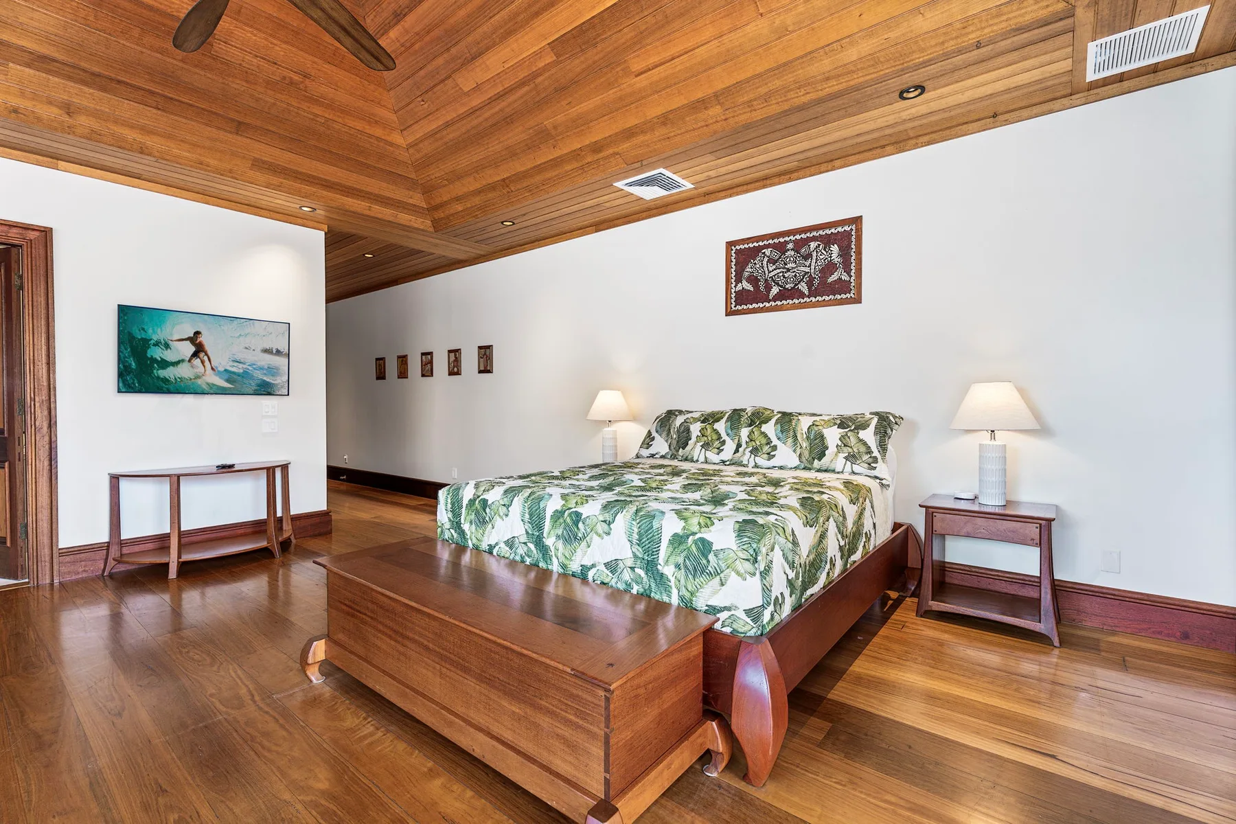 A bedroom with a wooden bed dressed in green floral bedding and matching bedside tables.