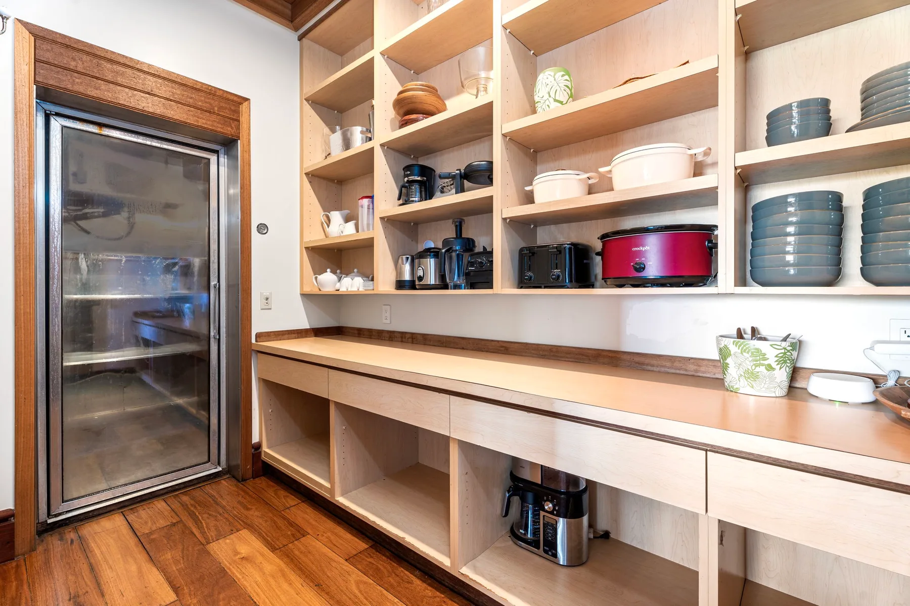 A kitchen storage area with open wooden shelving and a countertop.