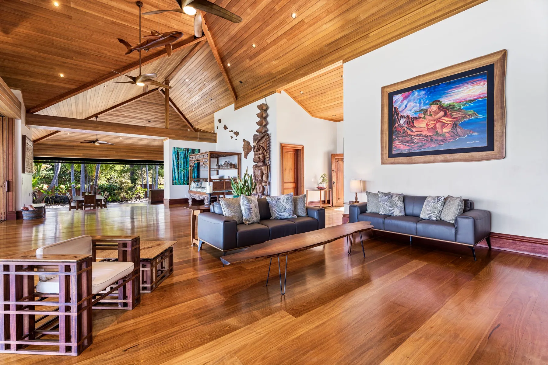 A spacious living room has seating beneath a high wooden ceiling.