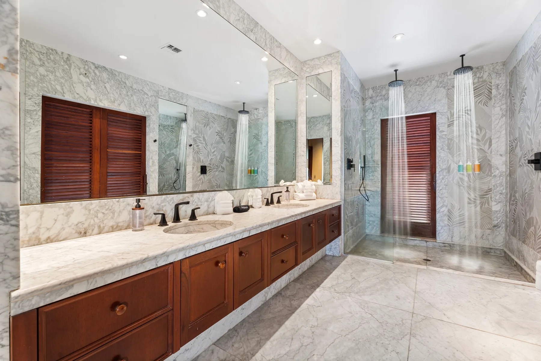 A spacious bathroom with a long vanity, large mirror, and glass shower.