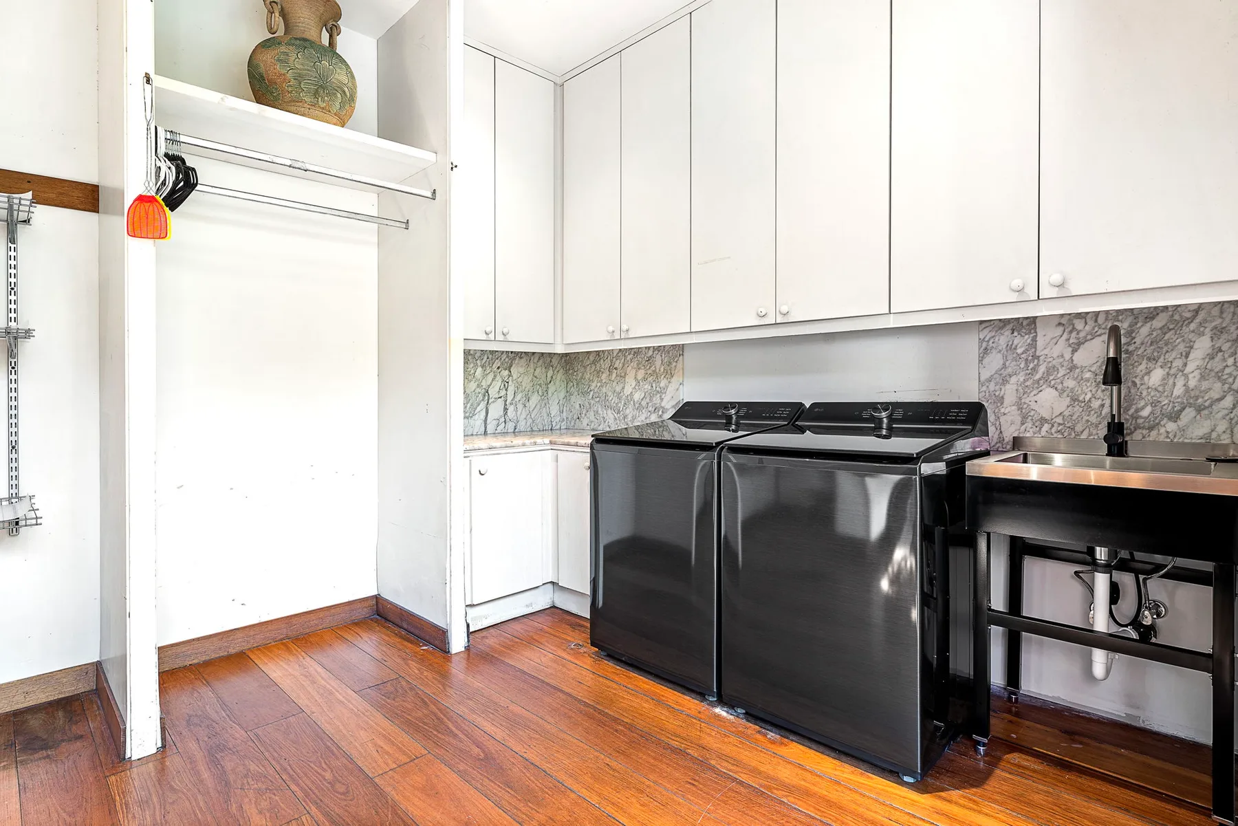A kitchen with black appliances, white cabinets, and a wood floor.