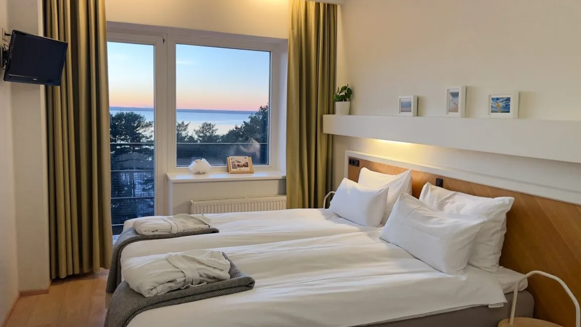 Habitación estándar de LaSpa con dos camas individuales, vistas al mar a través de un gran ventanal, acceso al balcón e interior de estilo nórdico sereno