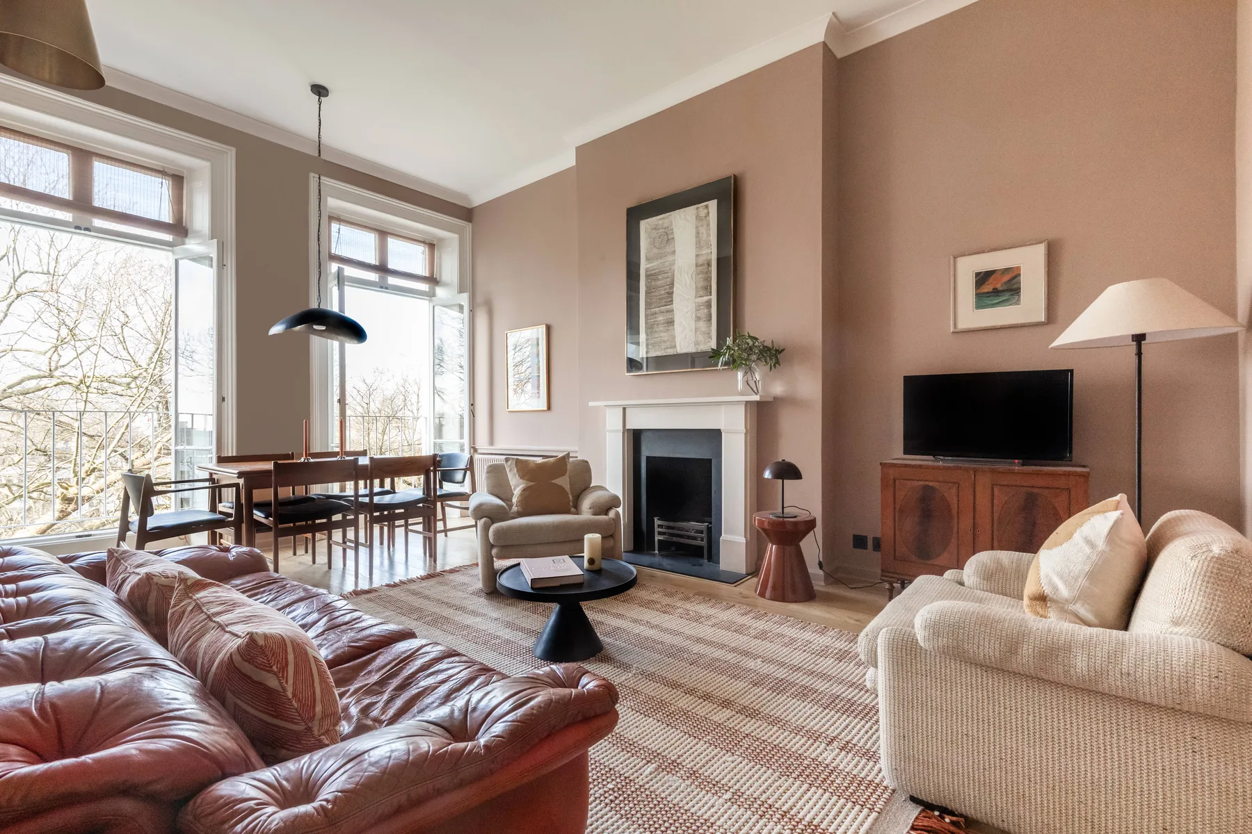 A living room with sofas, a fireplace, and tall windows.