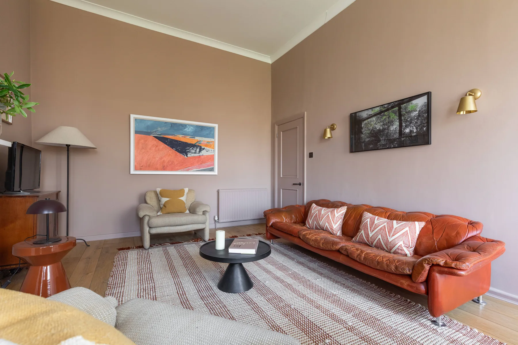 A living room with a leather sofa, armchair, and coffee table on a patterned rug.