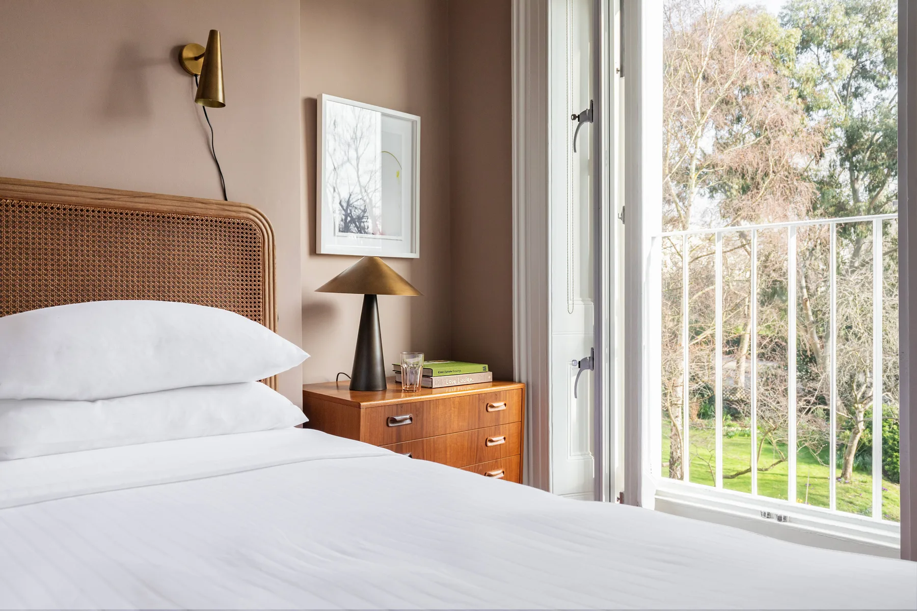 A bedroom with a neatly made bed beside an open balcony view.