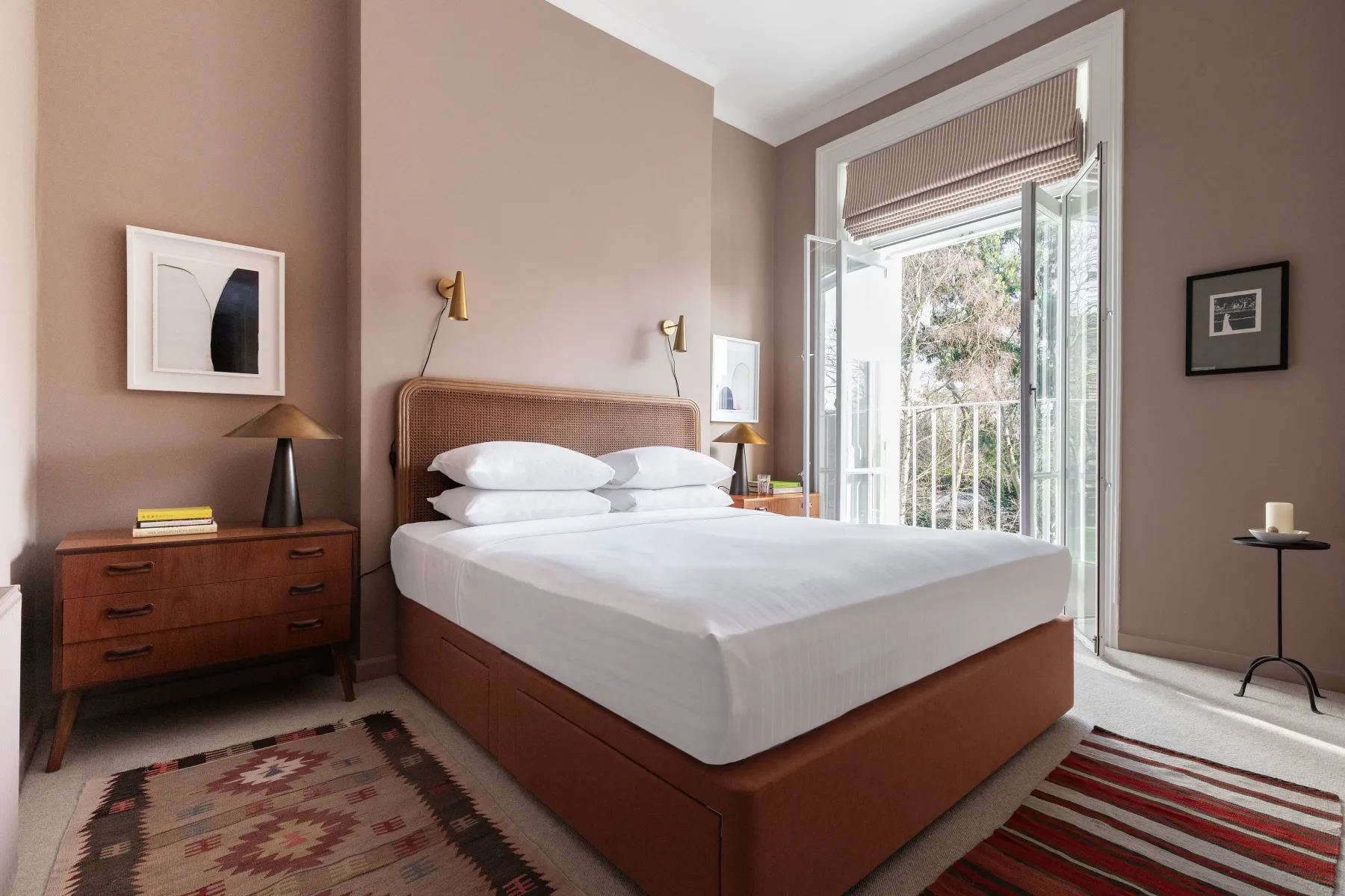 A bedroom with a neatly made bed beside an open balcony door.