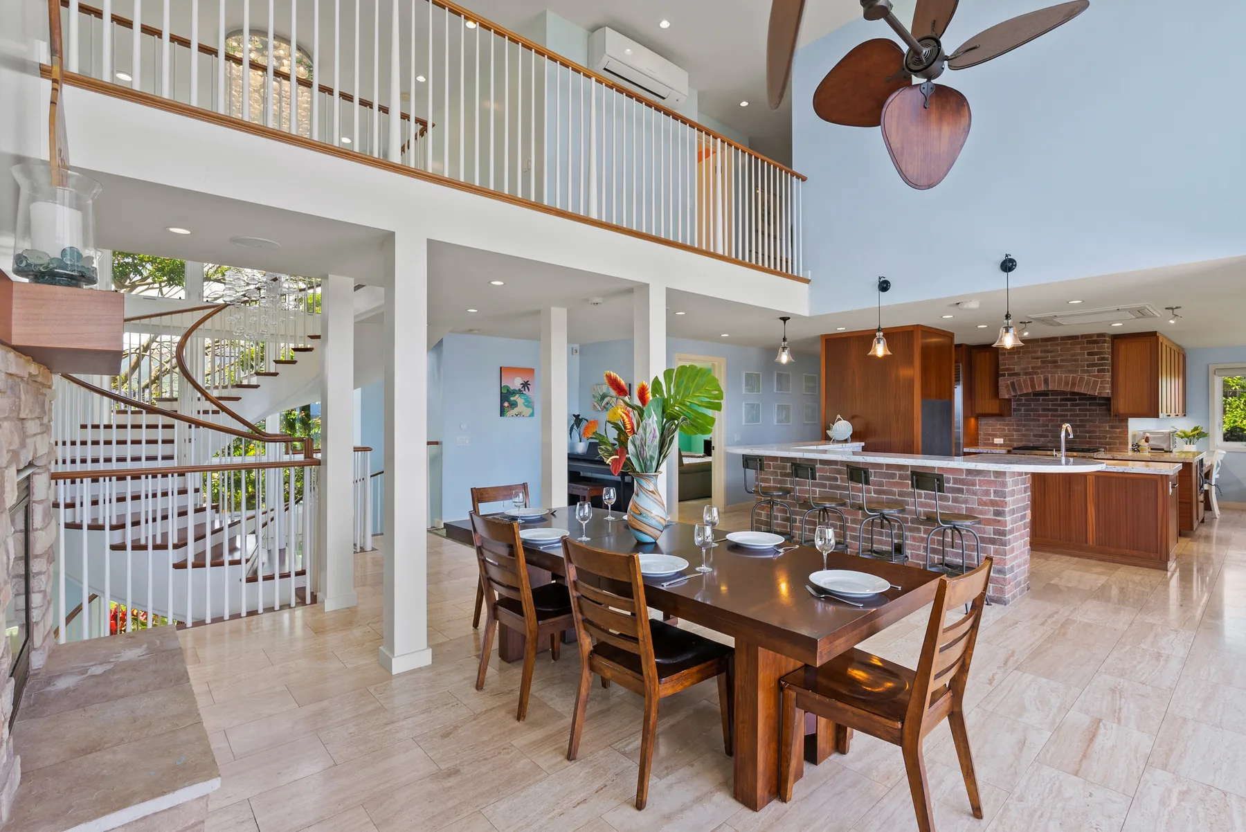 Un comedor abierto con una mesa de madera junto a una cocina y una escalera.