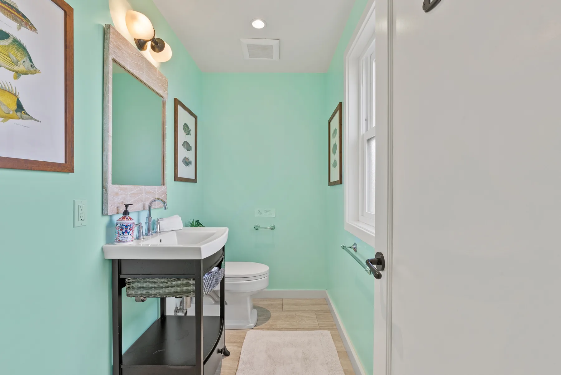 Baño verde menta con lavabo, inodoro y ventana.