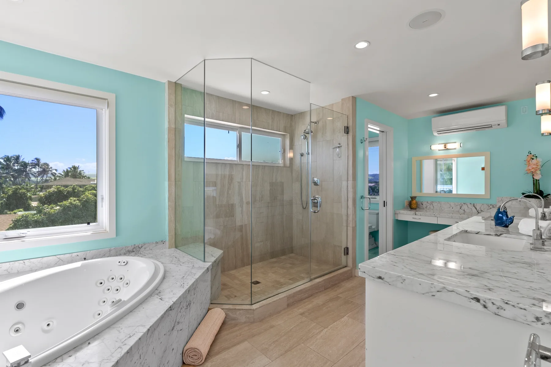 Un baño luminoso con ducha de vidrio, bañera y tocador de mármol.