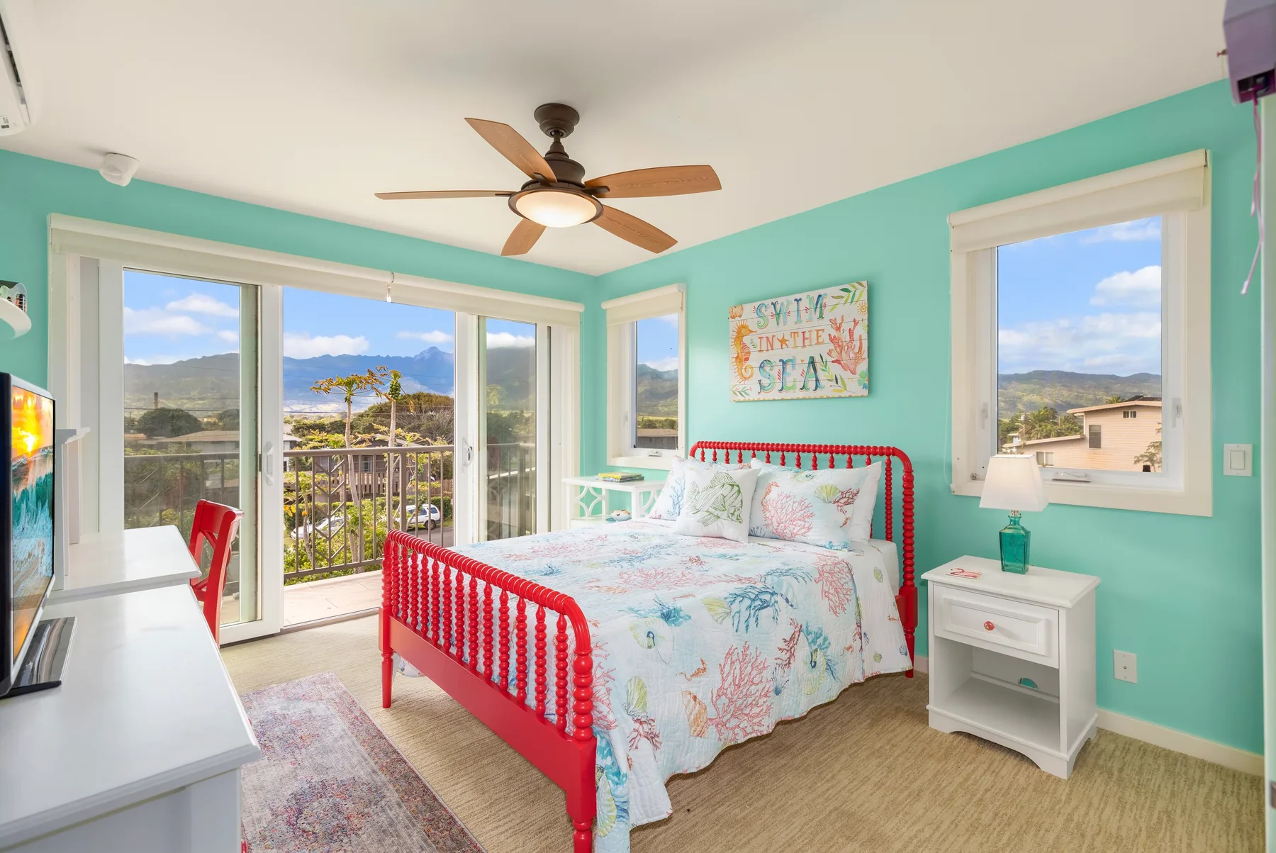 Un dormitorio luminoso con una cama de estructura roja y ventanas con vistas al paisaje.