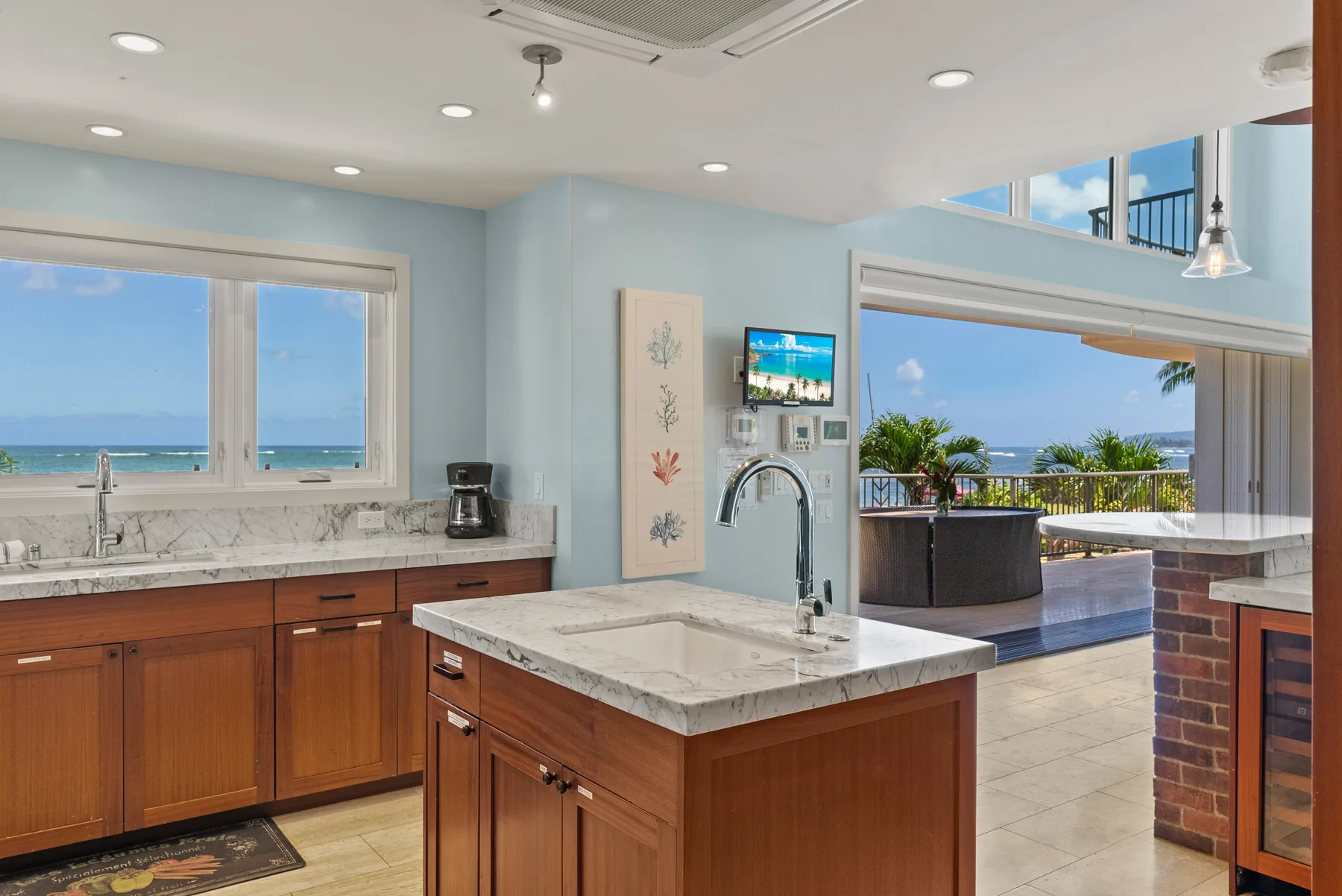 Una cocina luminosa con una isla central y vistas al mar por las ventanas.
