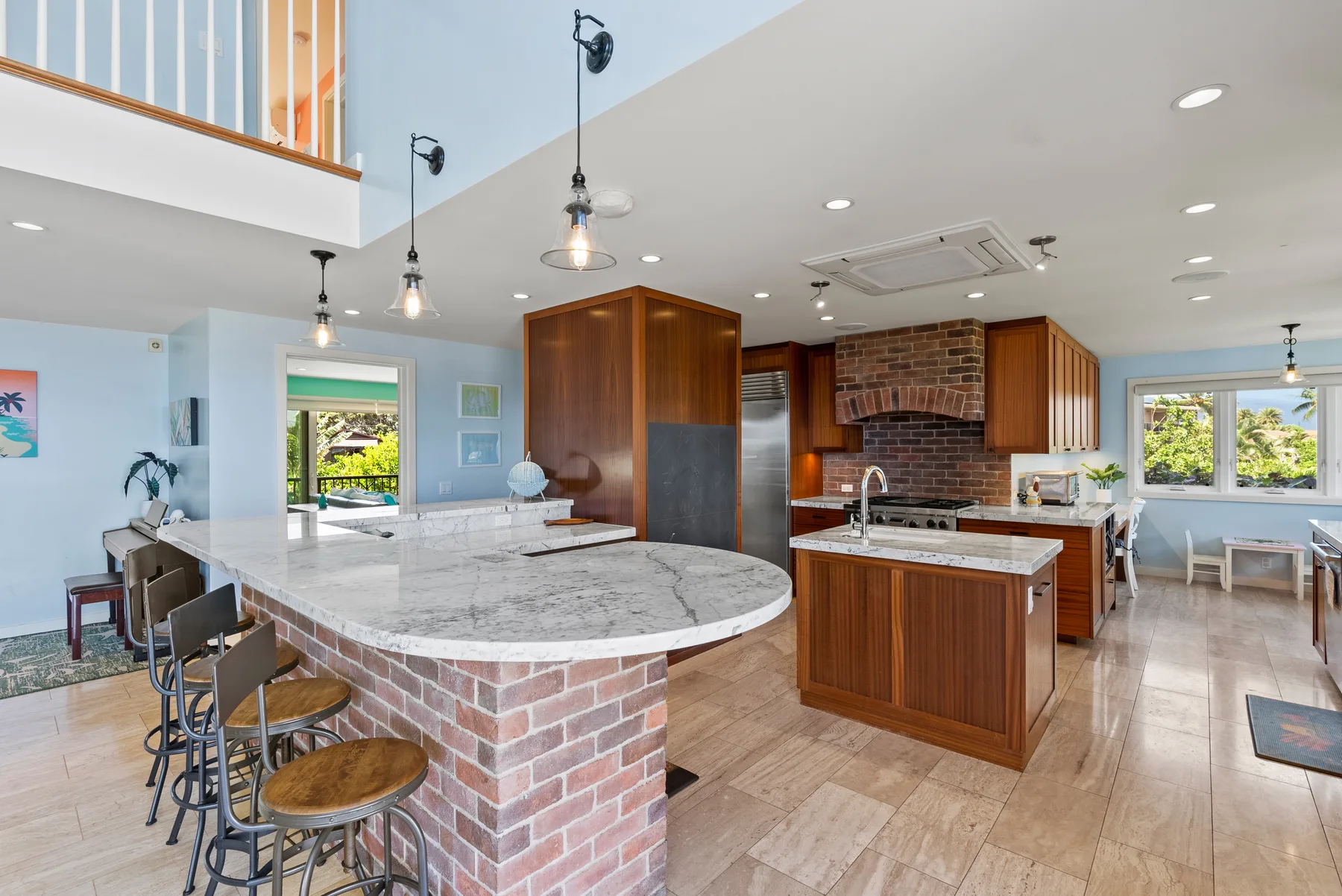 Cocina abierta con una isla larga, base de ladrillo y gabinetes de madera.